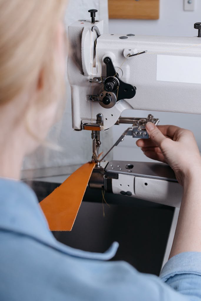 A Person Sewing a Yellow Leather Fabric