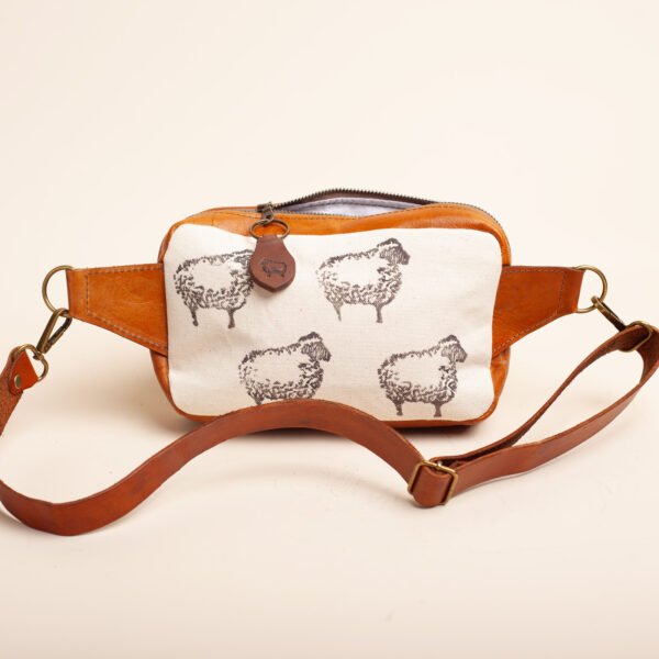brown-sheep-back the back of a fanny pack in brown leather and canvas printed with black sheep