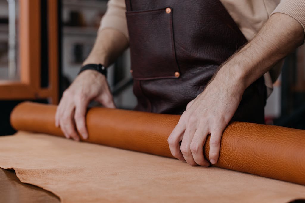 Close-Up Shot of a Person Rolling a Leather Textile